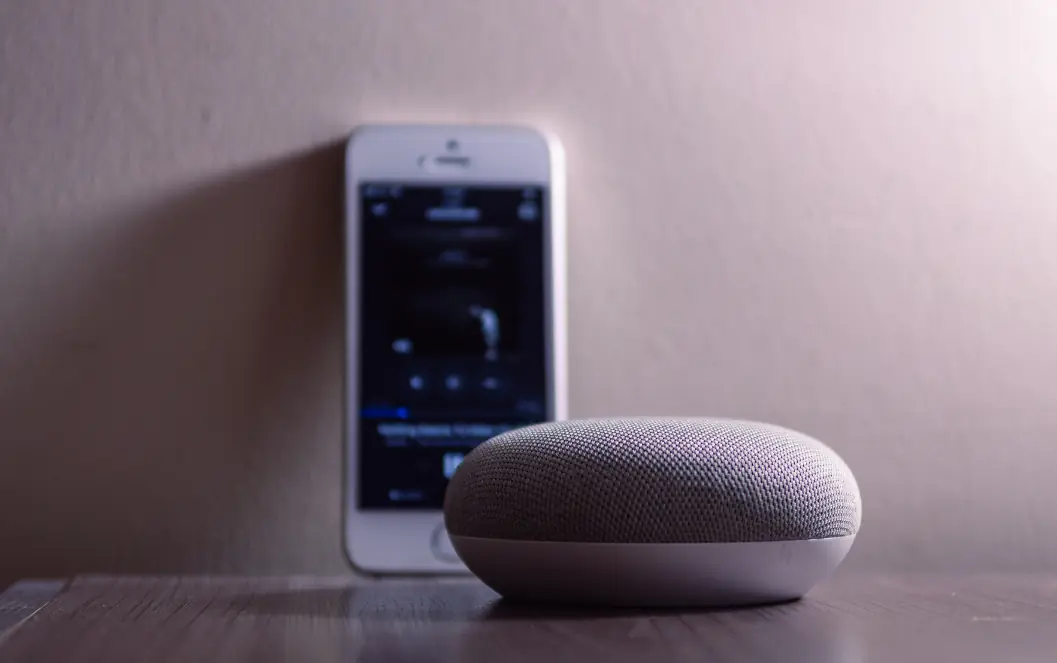 Smart speaker beside a smartphone for the SEO vs Google Ads comparison, supporting organic and paid search intent