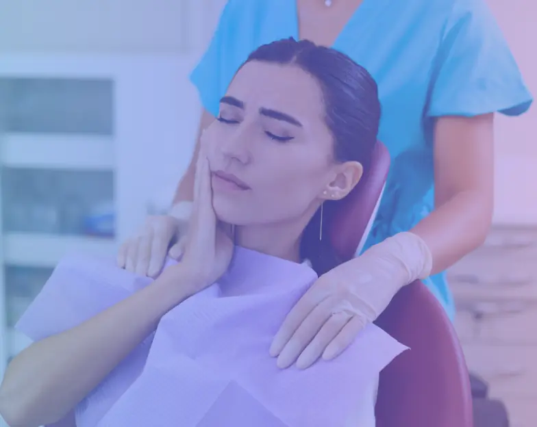 Medical and dental marketing in UAE: Woman holding her cheek in a dental chair with a clinician beside her for Emergency and Same-Day Dental Care