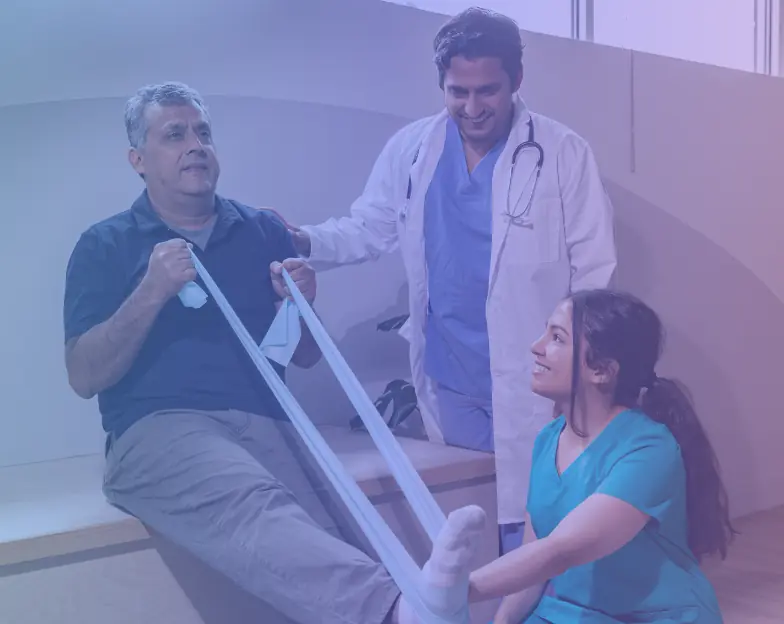 Medical and dental marketing in UAE: Seated man using a resistance band with two healthcare professionals nearby for Home Physiotherapy and Rehabilitation
