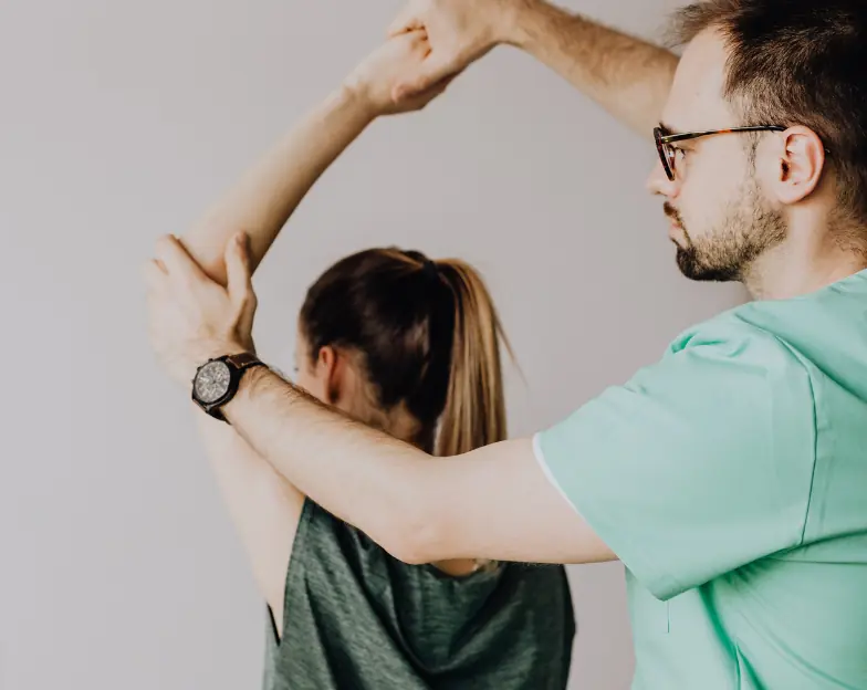 Medical and dental marketing in UAE: Practitioner guiding a woman's raised arm during a movement assessment for Physiotherapy and Allied Health Practices, supporting specialty-led healthcare marketing